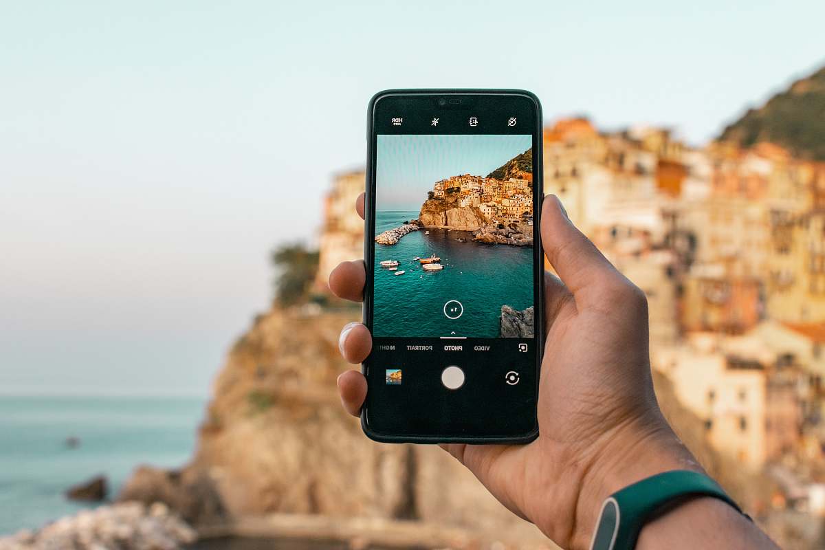cell phone person holding a phone near cliff during daytime mobile phone